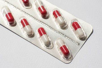 packings of pills and capsules of medicines on white background