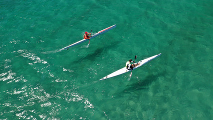Aerial photo of fit athletes competing on sport canoe in tropical exotic bay with crystal clear...