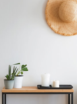 Modern minimalist light interior in details. Straw hat on the wall over the small wooden console