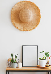 Modern minimalist light interior in details. Straw hat on the wall over the small wooden console