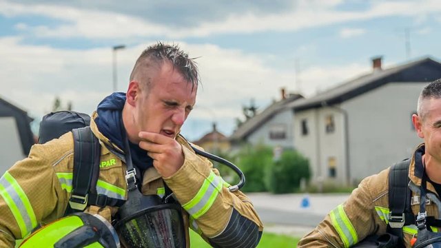 A firefighter is wiping his face off water after a successful firefighting practise.