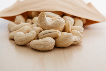 Cashew nuts and packaging bag on a floor wooden ,closeup