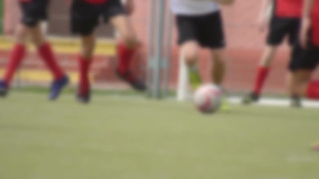 Caucasian boys play football on a green field, the guy makes a feint, background, slow motion, blurred