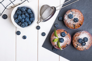 Delicious muffins with blueberries on the white wooden table