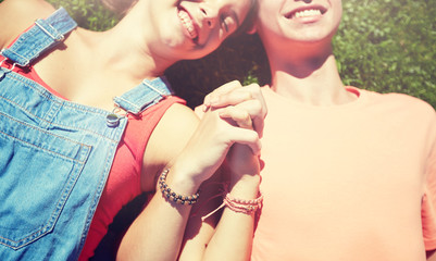 love and people concept - close up of happy teenage couple lying on grass and holding hands with...