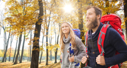 adventure, travel, tourism, hike and people concept - couple of travelers with backpacks over autumn park background