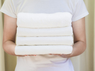 Close-up woman holding white folded clean towels