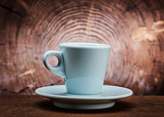 white ceramic coffee cup on vintage wood background with cross cut of tree trunk