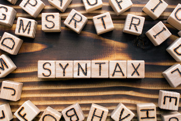 syntax  composed of wooden cubes with letters, grammatical arrangement of words in a sentence concept, the random letters around, top view on wooden background