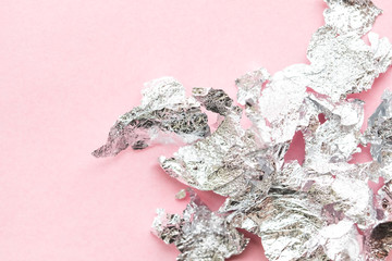 Abstract background made of crumpled foil  on pink paper background. Place for text. 