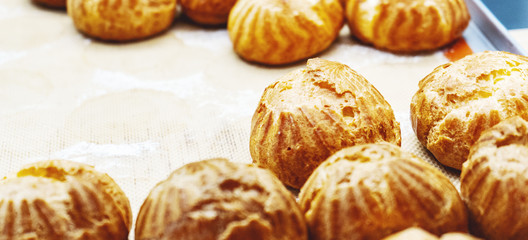Cake profiteroles just out of the oven on parchment with a copy  space.
