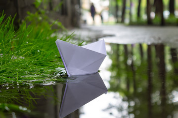 The paper boat floats on the stream after a heavy rain between the streets of the city