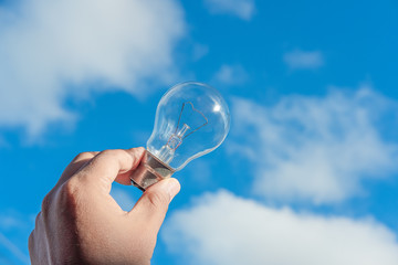 hand holding light bulb and blue sky background