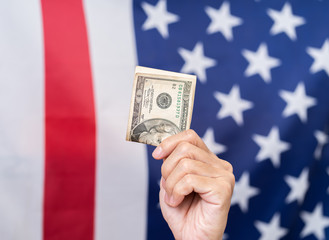 Hand holding dollar with America flag background