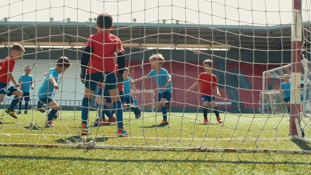 Boys playing soccer, getting long pass, attacking goal post and making goal
