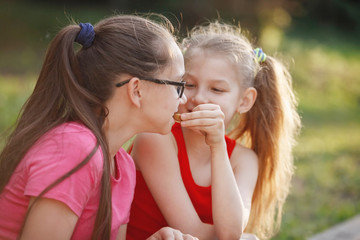 Two teen girls laugh and talk in the city park.