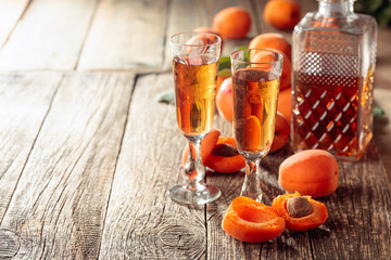 Apricot liquor and fresh apricots on a old wooden table.
