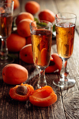Apricot liquor and fresh apricots on a old wooden table.