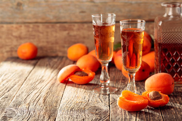 Apricot liquor and fresh apricots on a old wooden table.