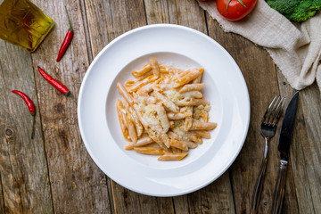 Penne four cheese on white plate on wooden table