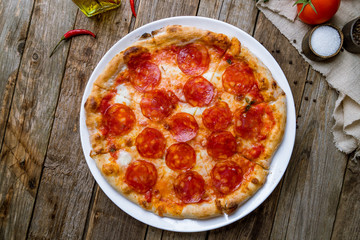 Pepperoni pizza on plate on wooden background