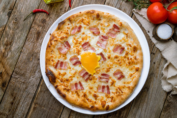Carbonara pizza with bacon and egg on wooden background
