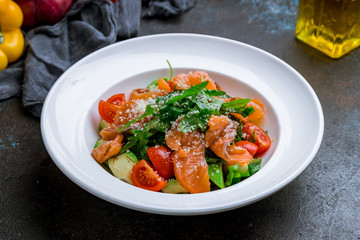 vegetable salad with avocado and salmon on dark concrete background