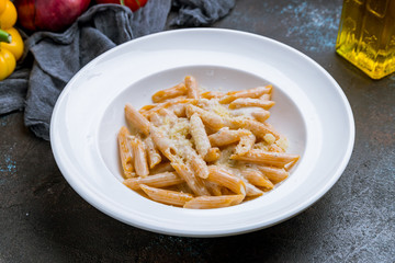 Penne four cheese on dark concrete background