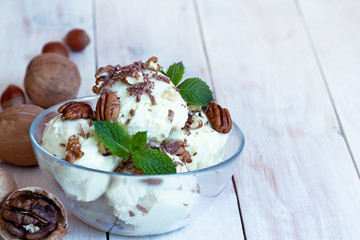 close up Vanilla ice cream with mint, macadamia and pecan nuts and chocolate. Ice cream decoration. Summer, sweet food. Food background. Natural Tasty delicious chocolate dessert.