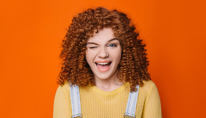 woman with curly red hair winking eye and open mouth with big smile