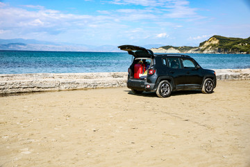Obraz na płótnie Canvas Black summer car on the sunny sandy beach. Blue clear sunshine sky view in distance. 