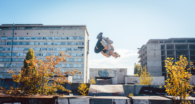 Acrobat man doing somersault mid air on urbex session