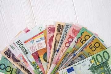 Obraz premium Colorful international banknotes in fan on light wooden table