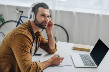 Fototapeta premium good-looking man listening music, holding pencil and looking away