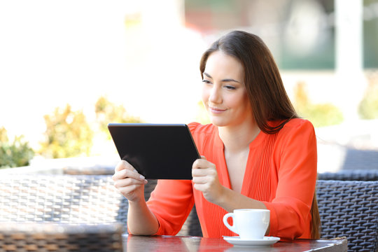 Serious woman watching tablet online content in a bar