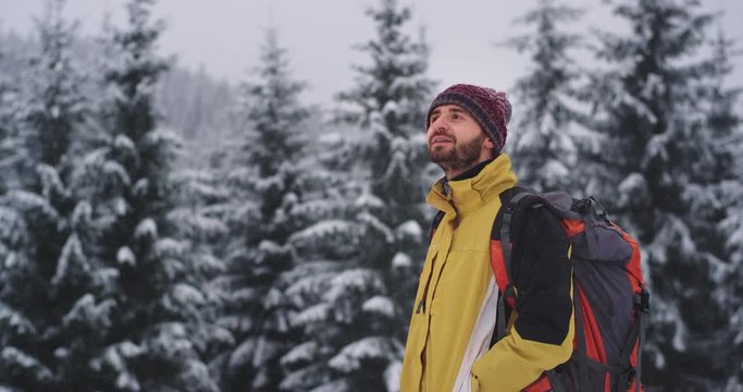 In a hard winter day happy and enthusiastic tourist feeling excited in the middle of snowy forest he wearing a red hat , enjoying the snow