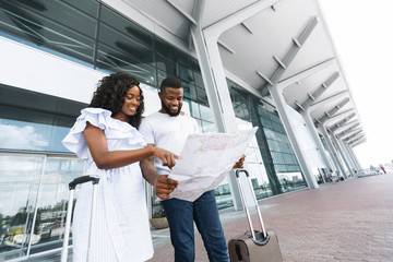 Young african american couple looking at map at airport building