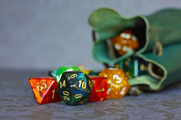 Different colorful role playing dice coming out of green storage leather bag