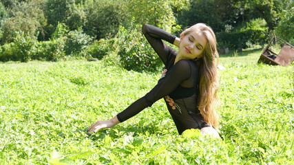 Portrait of a young smiling blonde woman lying on green grass.