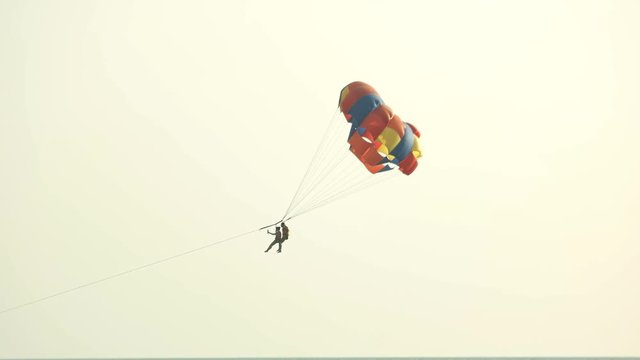 Air parachute on clear sky background. Couple parasailing at summer resort. Summer activity concept. Romantic rest together.