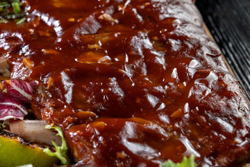 Pork ribs with sauce laid out on a wooden board.