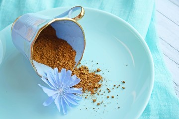 Ground chicory and blue chicory flowers on blue background.Alternative to coffee.