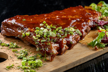 Pork ribs with sauce laid out on a wooden board.