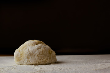 Fresh dough on table on dark background