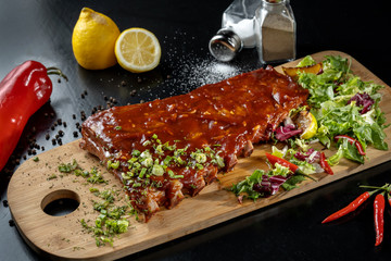 Pork ribs with sauce laid out on a wooden board.