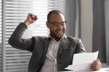 Happy african businessman winner reading letter celebrating good news