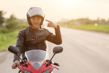 Handsome motorcyclist point the finger to his helmet
