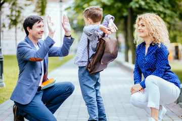Education, childhood, family and people concept. Front view of elementary student boy with family...