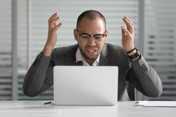 Angry african business man using laptop mad about computer problem