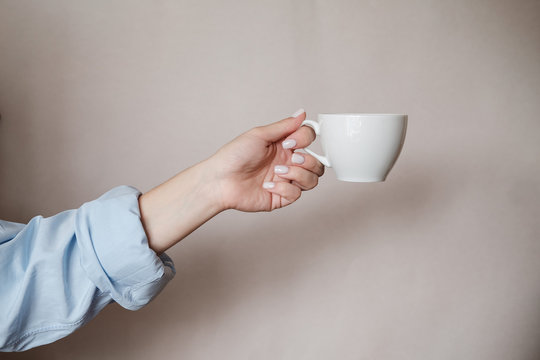 Woman Holding Cup Of Coffee. Female Hands With Cup Of Black Tea On Beige Background. Close Up